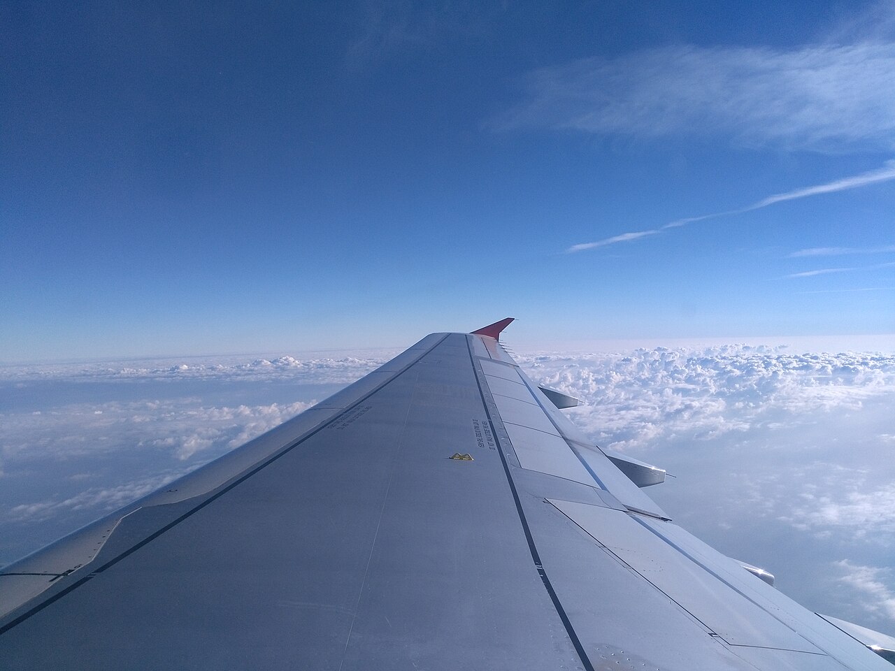 Airplane wing seen above the clouds from a passenger window